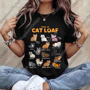 Może przedstawiać: Czarny t-shirt z napisem "TYPES OF CAT LOAF" i siatką ilustracji kotów, z których każdy reprezentuje inny rodzaj "chleba dla kota", w tym "Whole Grain", "Cheesy Garlic" i "Cinnamon". Odzież codzienna.