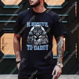 May include: Black t-shirt with a wolf graphic and the text "BE RESPECTFUL TO DADDY" in light blue. The graphic features a wolf surrounded by other wolves. The shirt is short-sleeved.