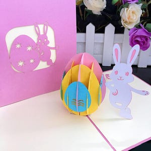 Tarjeta de felicitación de Pascua 3D creativa con un conejo y huevos de colores: un diseño tridimensional único.