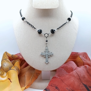 Sparkling rhinestone silver cross dangles from hypoallergenic black chain necklace.