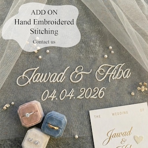 May include: An image featuring hand-embroidered text that reads "Jawad & Hiba" and the date "04.04.2026". The image also includes ring boxes in pink, blue, and cream, along with a wedding invitation. The text "ADD ON Hand Embroidered Stitching Contact us" is also visible.