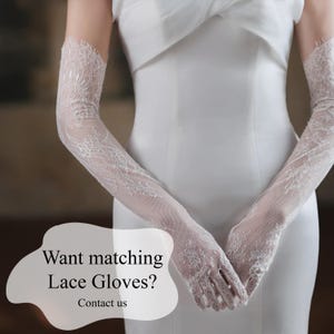 May include: White lace gloves with intricate floral patterns, extending to the upper arm. The gloves are paired with a white dress. Text on the image reads: "Want matching Lace Gloves? Contact us."