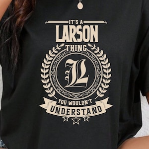 May include: Black t-shirt with a white graphic that says "It's a Larson Thing" with a stylized "L" in a wreath and the text "You wouldn't understand" below.