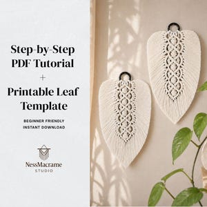 May include: Two cream-colored macrame leaf wall hangings with black metal rings for hanging. The leaves have intricate woven patterns. The image also includes text: Step-by-Step PDF Tutorial + Printable Leaf Template.