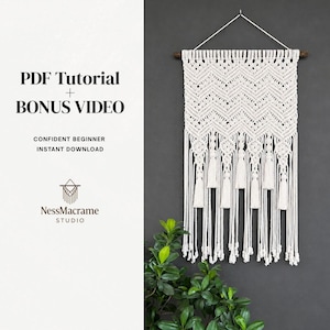 Pode incluir: Uma tapeçaria de parede de macramé branco com um padrão de chevron e borlas, suspensa por um pino de madeira. A imagem inclui o texto "PDF Tutorial + Bonus Video" e "Confident Beginner Instant Download."