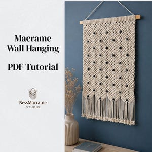 May include: A macrame wall hanging featuring a diamond pattern with black beads, suspended from a wooden dowel. The text on the left reads Macrame Wall Hanging PDF Tutorial and includes the NessMacrame Studio logo above the brand name.