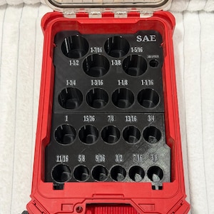 May include: Red plastic tool organizer with a clear lid, holding black inserts with various sized holes. The organizer is labeled "SAE" and includes measurements like 1-7/16 and 1-5/16 inches.