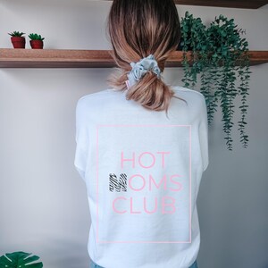May include: White sweatshirt with a pink rectangle and the text "HOT MOMS CLUB" in black and white zebra print.