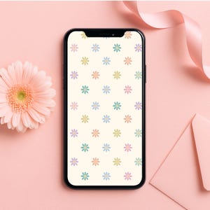 May include: A smartphone with a white background and a pattern of pastel-coloured daisies. The phone is on a pink surface.