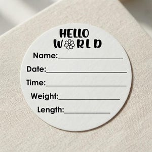 Może przedstawiać: Okrągła biała naklejka z czarnym napisem HELLO WORLD, w którym mała ikona kwiatka zastępuje literę O. Pod nagłówkiem znajduje się pięć poziomych linii z etykietami Name, Date, Time, Weight oraz Length do wpisywania szczegółowych informacji.