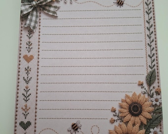 May include: A rectangular sheet of stationery featuring a lined writing area, decorated with embroidered-style sunflowers, green gingham bows, and small bees. The border includes floral motifs, hearts, and a patch with the text Grow Kindness.