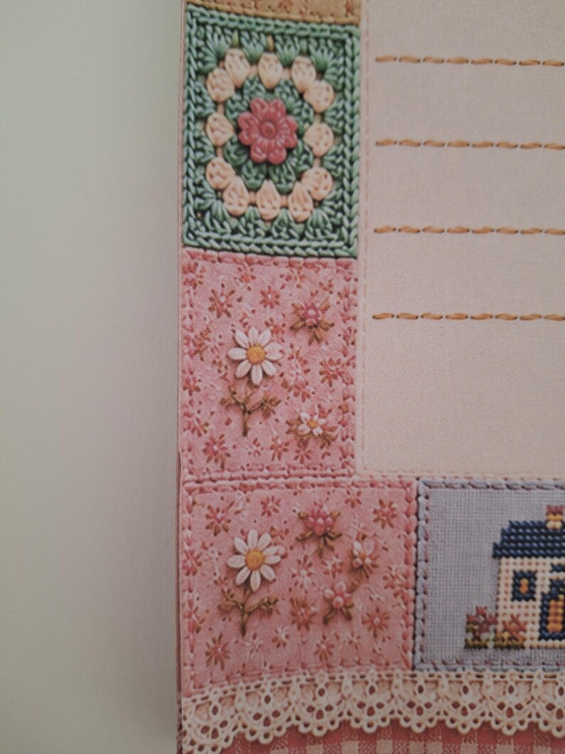 May include: A stationery sheet featuring a patchwork-style border with a crochet-look square, pink floral fabric patterns, and a small house illustration. The page includes horizontal stitched lines for writing and a white lace trim at the bottom edge.