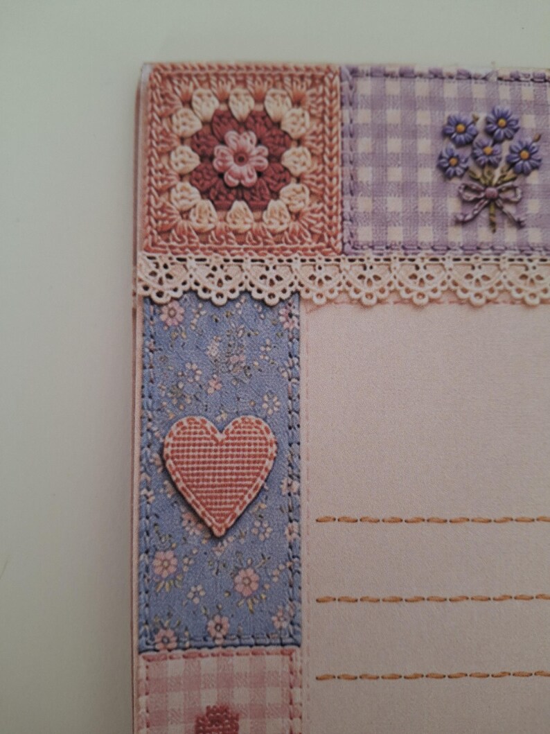 May include: A decorative stationery card featuring a patchwork design with a crochet-style square, a purple gingham panel with a floral bouquet, a lace trim, and a blue floral strip with a pink heart appliqu&eacute;, alongside lined writing space.