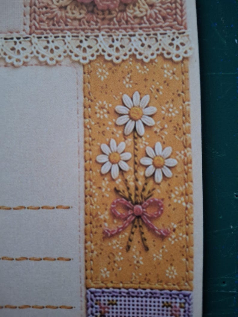Puede incluir: Una hoja de papel de carta decorativa con un borde vertical sobre un fondo amarillo mostaza estampado con peque&ntilde;as flores blancas. El borde muestra un ramo de tres margaritas blancas con centros amarillos atadas con un lazo rosa.