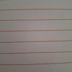 May include: A light grey fabric featuring multiple horizontal rows of parallel stitching in a tan thread colour. The stitching pattern consists of evenly spaced, small, dashed lines that run across the entire width of the textile surface.