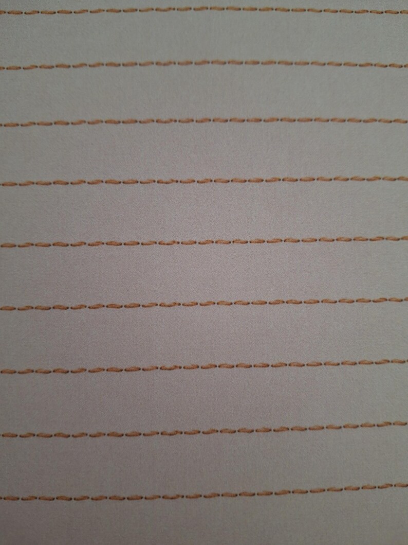 May include: A light grey fabric featuring multiple horizontal rows of parallel stitching in a tan thread colour. The stitching pattern consists of evenly spaced, small, dashed lines that run across the entire width of the textile surface.