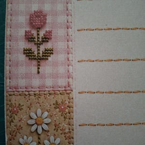 Puede incluir: Papel de carta con un borde vertical que presenta una secci&oacute;n superior de flores azules, una secci&oacute;n central de cuadros rosas con una flor en punto de cruz y una secci&oacute;n inferior de flores beige con margaritas blancas y l&iacute;neas discontinuas.