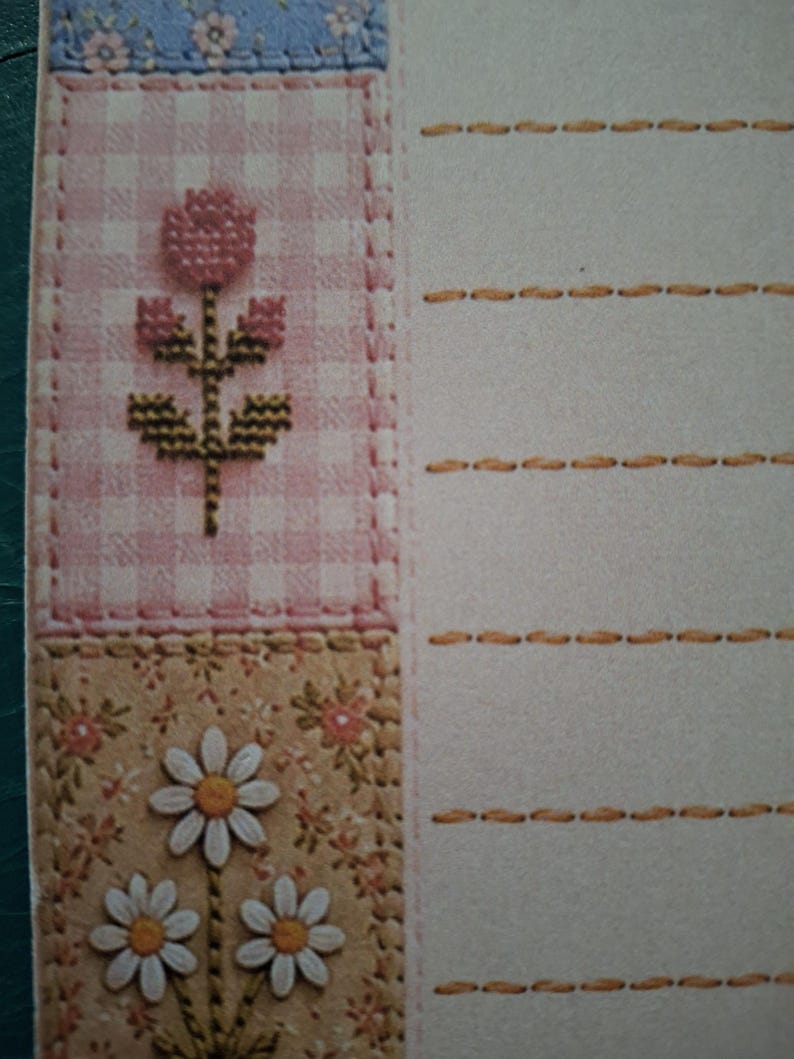 Puede incluir: Papel de carta con un borde vertical que presenta una secci&oacute;n superior de flores azules, una secci&oacute;n central de cuadros rosas con una flor en punto de cruz y una secci&oacute;n inferior de flores beige con margaritas blancas y l&iacute;neas discontinuas.