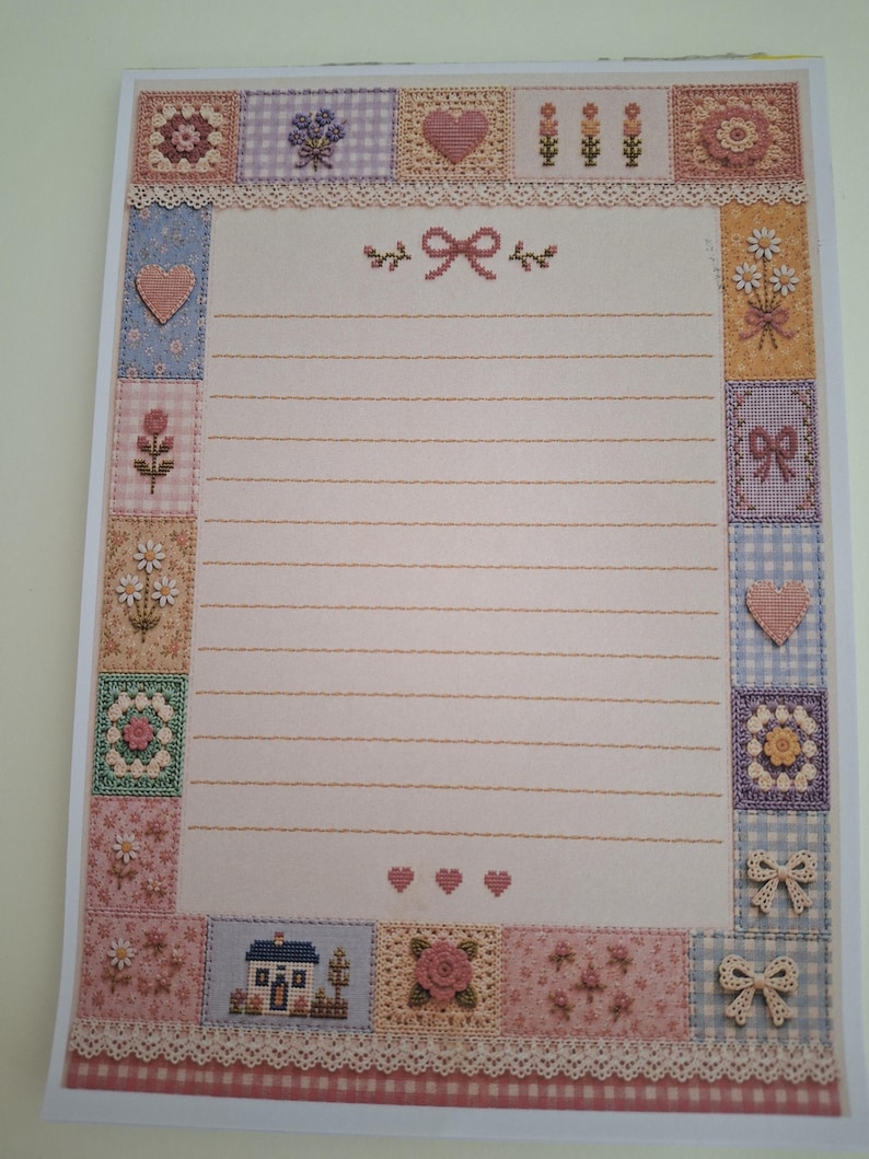 Puede incluir: Una hoja de papel de carta rectangular con un &aacute;rea central de l&iacute;neas horizontales para escribir, enmarcada por un borde de varios cuadrados. Los cuadrados muestran patrones de punto de cruz de flores, corazones, lazos y una casa en tonos pastel.