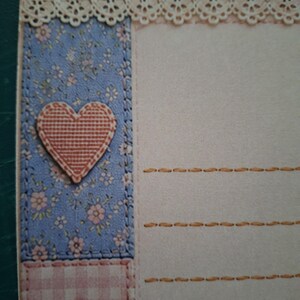 Puede incluir: Una hoja de papel de carta con una zona de escritura color crema y l&iacute;neas horizontales naranjas discontinuas. El borde izquierdo muestra un patr&oacute;n floral azul con un coraz&oacute;n texturizado, mientras que la parte superior est&aacute; adornada con encaje y un cuadro vichy morado.