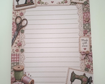 May include: A rectangular stationery sheet with lined paper, featuring a border of pink floral patterns, lace, buttons, scissors, thread spools, and sewing machines. The text reads "Sewing mends the Soul" at the top and "Made with Love" on the right side.