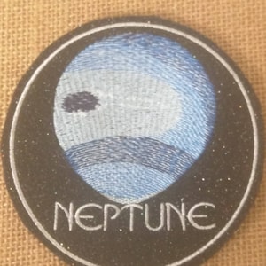 May include: A black and white embroidered patch with a blue planet design and the word "NEPTUNE" in white lettering.