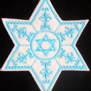 May include: A white felt star with a blue embroidered outline and a blue six-pointed star in the center.
