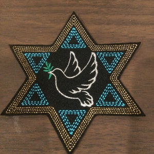 May include: A black six-pointed star with a white dove holding an olive branch in its beak. The star is outlined in gold and blue thread. The dove is centred in the star.