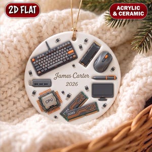 May include: A round white ceramic ornament featuring a gold hanging string and a printed pattern of computer hardware including a keyboard, mouse, CPU, RAM sticks, and monitor. The center displays the name James Carter and the year 2026.
