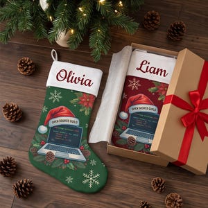 May include: Two Christmas stockings with white cuffs personalized with the names Olivia and Liam. The green and red stockings feature a graphic of a laptop displaying code under the text Open Source Guild, surrounded by pine and snowflakes.