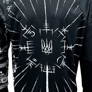 May include: Black sweatshirt with a white print of a Ukrainian trident surrounded by stylized symbols. The print is centered on the chest of the sweatshirt.