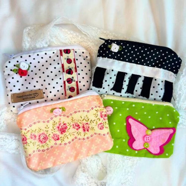Puede incluir: Cuatro monederos con cremallera hechos a mano con varios dise&ntilde;os. Uno es blanco con lunares negros y una cinta de mariquitas, otro es negro con lunares blancos y un dise&ntilde;o de teclas de piano, un tercero es melocot&oacute;n con rosas rosas y el &uacute;ltimo es verde con una mariposa rosa.