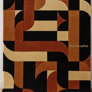 Pode incluir: Tapete geom&eacute;trico em preto, bege e laranja enferrujado. O tapete apresenta um design repetitivo de formas curvas e retangulares. O texto "RugLegacyShop" &eacute; vis&iacute;vel no canto inferior direito. O tapete &eacute; retangular.