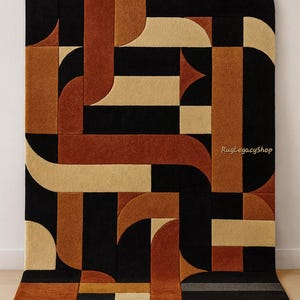 Pode incluir: Tapete com padr&atilde;o geom&eacute;trico em preto, bege e laranja enferrujado. O tapete apresenta um padr&atilde;o repetitivo de formas curvas e retangulares. O texto "RugLegacyShop" &eacute; vis&iacute;vel no tapete. Este tapete &eacute; adequado para salas de estar e quartos.