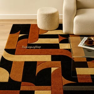Pode incluir: Tapete com padr&atilde;o geom&eacute;trico em preto, castanho e bege. O tapete apresenta um design moderno com formas curvas e retangulares. Um pufe e um sof&aacute; bege est&atilde;o no fundo. O tapete est&aacute; sobre um ch&atilde;o de madeira.