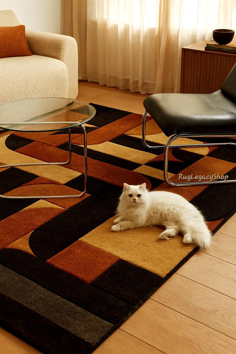 Pode incluir: Um tapete moderno com um padr&atilde;o geom&eacute;trico em tons de castanho, preto e dourado. Um gato branco est&aacute; deitado no tapete. O tapete apresenta um design contempor&acirc;neo com formas curvas e retangulares. O texto "RugLegacyShop" &eacute; vis&iacute;vel.