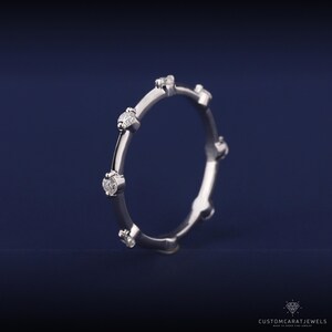 Handshot of white gold diamond station band with minimalist design, perfect for everyday wear.
hand photo ring, diamond sparkle, white gold ring, dainty style, stacking band, everyday jewelry, bridal elegance, wedding accessory, anniversary ring, fine jewelry, chic look, simple band, elegant ring, subtle sparkle, daily ring