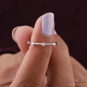 Macro shot showing diamond station band’s clarity and polished white gold finish.
macro ring view, diamond clarity, station placement, white gold shine, dainty sparkle, stacking band, fine jewelry, wedding accessory, bridal band, anniversary ring, subtle elegance, everyday wear, chic design, modern ring, gold polish
