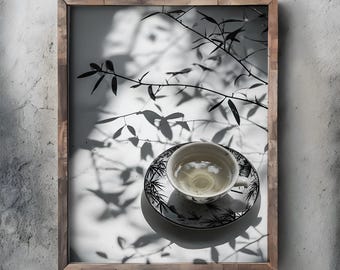 May include: A black and white photograph of a teacup and saucer with a leafy pattern. The teacup is filled with light-colored tea and the saucer is sitting on a white surface with shadows of leaves cast on it.