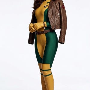 Pode incluir: Um traje composto por um macacão amarelo e verde, uma jaqueta de couro marrom com um emblema X-Men no ombro, luvas amarelas e botas amarelas de cano alto combinando. O conjunto inclui um cinto marrom com fivela e uma faixa verde.