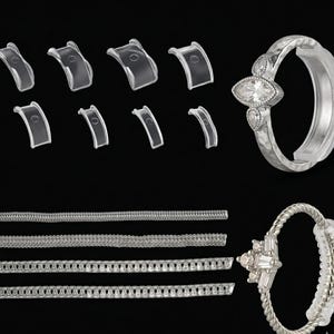 Puede incluir: Un surtido de ajustadores de talla de anillo de plástico transparente y dos anillos de plata con detalles de piedras preciosas. Un anillo presenta una piedra con corte marquesa, el otro un grupo de piedras con corte baguette. Los ajustadores son de varios tamaños.