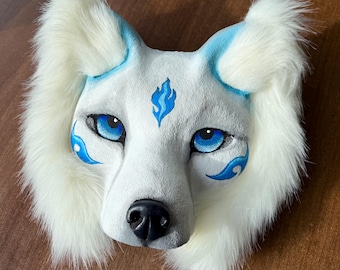 May include: White furry wolf mask with blue eyes and a blue flame design on the forehead.
