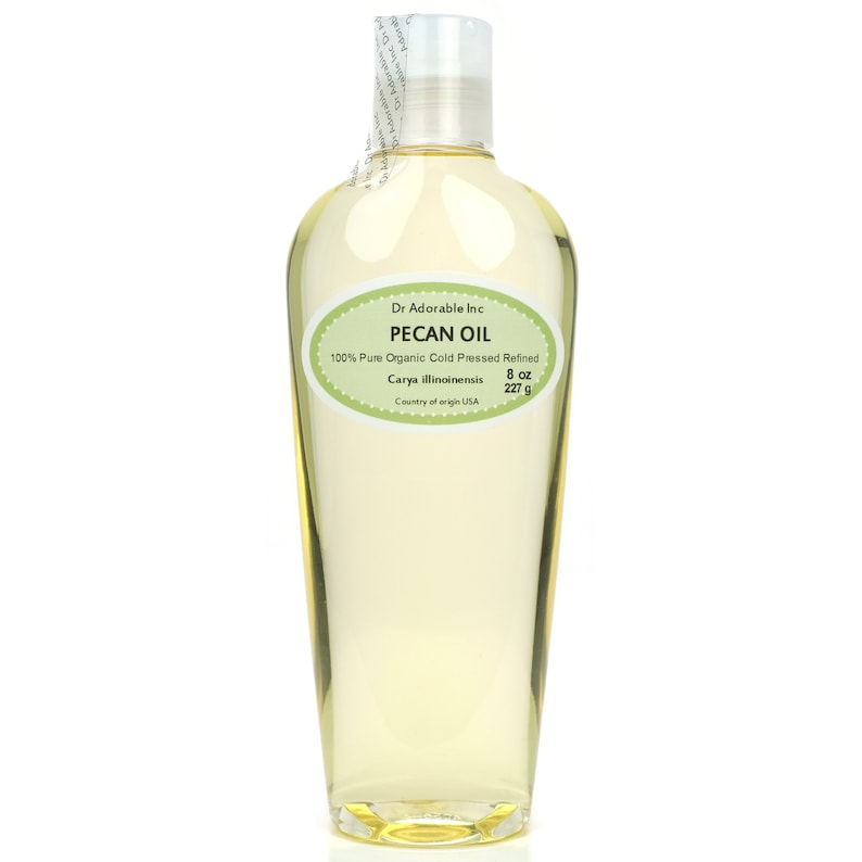 May include: A clear glass bottle of pecan oil with a green label that reads "Dr. Adorable Inc. Pecan Oil 100% Pure Organic Cold Pressed Refined Carya illinoinensis 8 oz 227 g Country of origin USA"