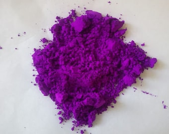 May include: A pile of vibrant purple pigment powder. The powder is finely ground and has a slightly grainy texture.