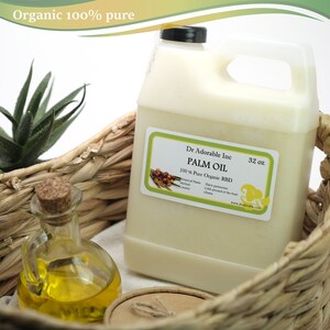 Op de afbeelding: Een 32-ounce container met 100% pure biologische palmolie, ge&euml;tiketteerd "Dr. Adorable Inc. Palmolie 100% Pure Biologische RBD". De container staat in een rieten mand met een klein glazen flesje olie op de voorgrond.