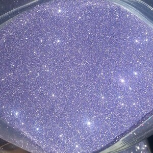 May include: A close-up view of a bag of purple glitter. The glitter is fine and sparkly, and it is perfect for crafting or decorating.