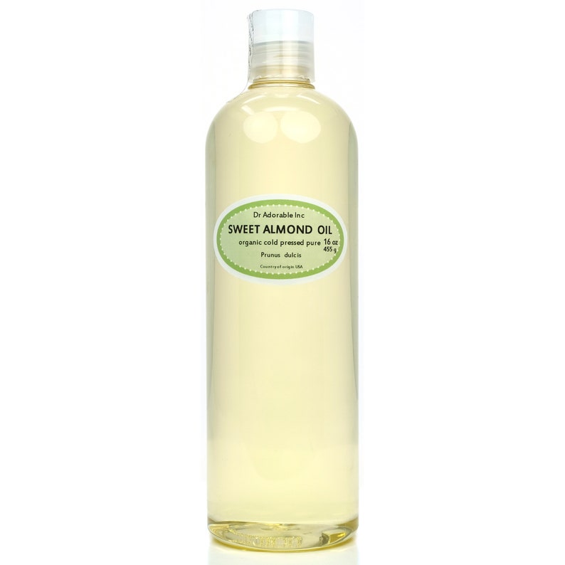 May include: A clear glass bottle of organic sweet almond oil, labeled with the brand name "Dr Adorable Inc." and the text "SWEET ALMOND OIL, organic cold pressed pure 16 oz, Prunus dulcis, Country of origin USA".