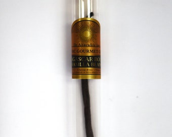 May include: A clear glass tube with a gold label containing a single Madagascar Bourbon vanilla bean. The label reads "Dr. Adorable Inc. Organic Gourmet Grade Madagascar Bourbon Vanilla Bean Gluten-Free Vegan". The top of the tube is sealed with a cork stopper with a gold label that reads "Best Before: 12/2020".