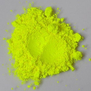 May include: A pile of bright yellow pigment powder. The powder is finely ground and has a smooth texture.