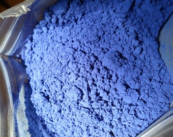May include: A close-up view of a bag filled with a fine, blue powder. The powder is a vibrant shade of blue and has a slightly grainy texture.